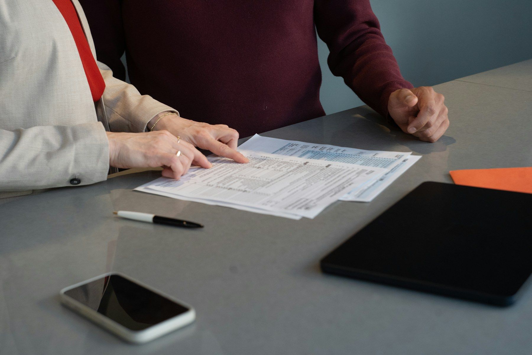 Two people reading printed documents together at a desk