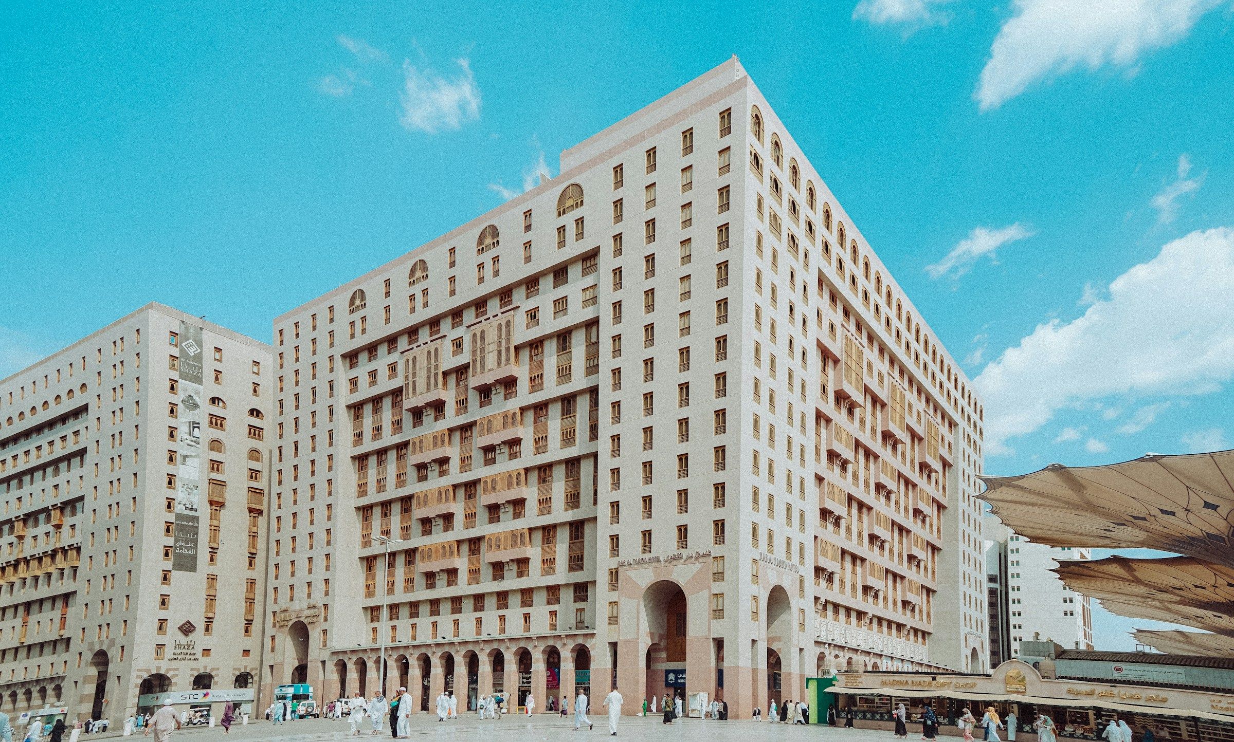 Hotels facing the plaza of Al-Masjid an-Nabawi in Madinah, with pilgrims crossing the square